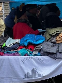 People selecting clothes from a table covered in jackets. The table has 