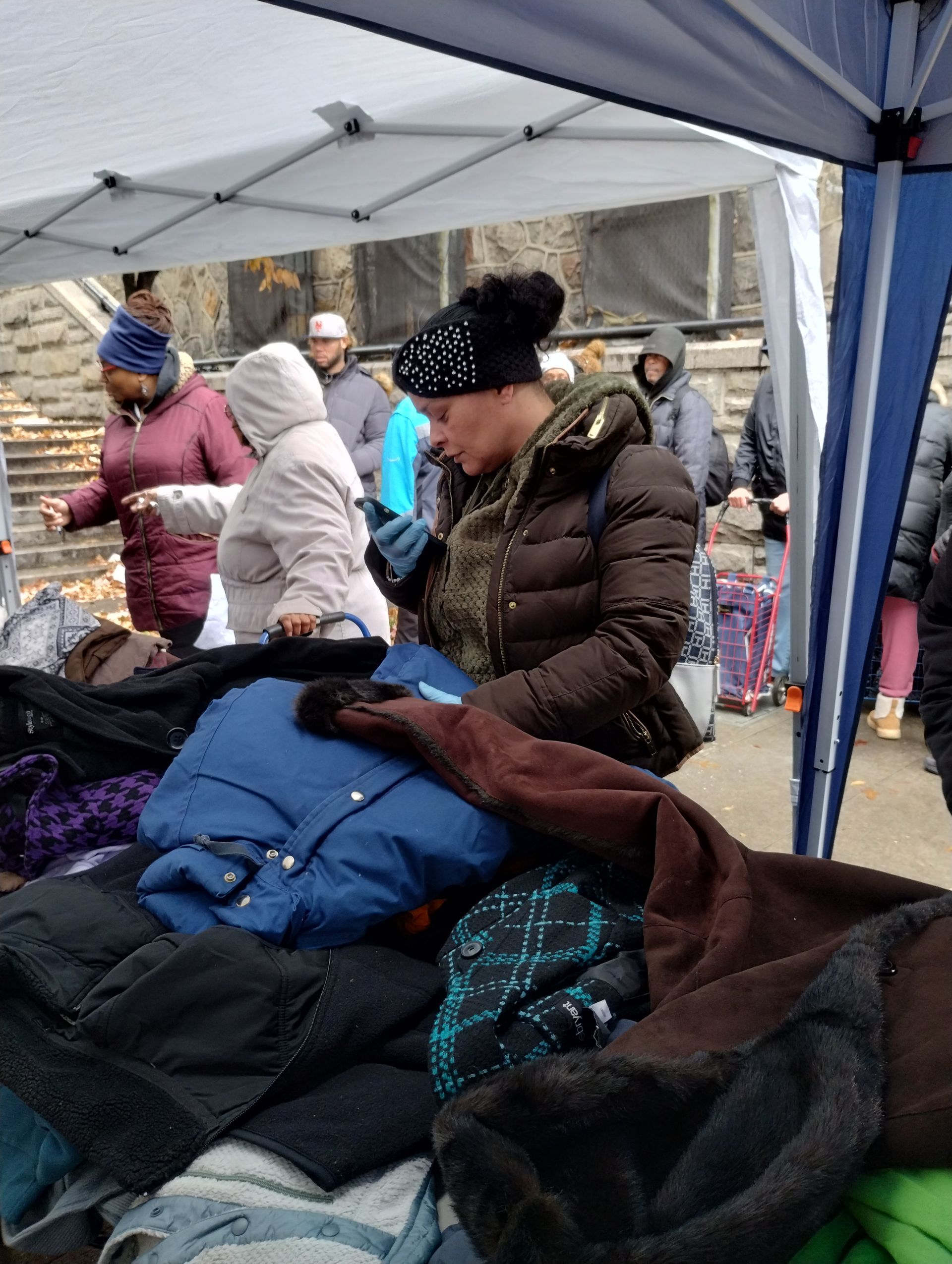 People browse coats at an outdoor clothing drive.