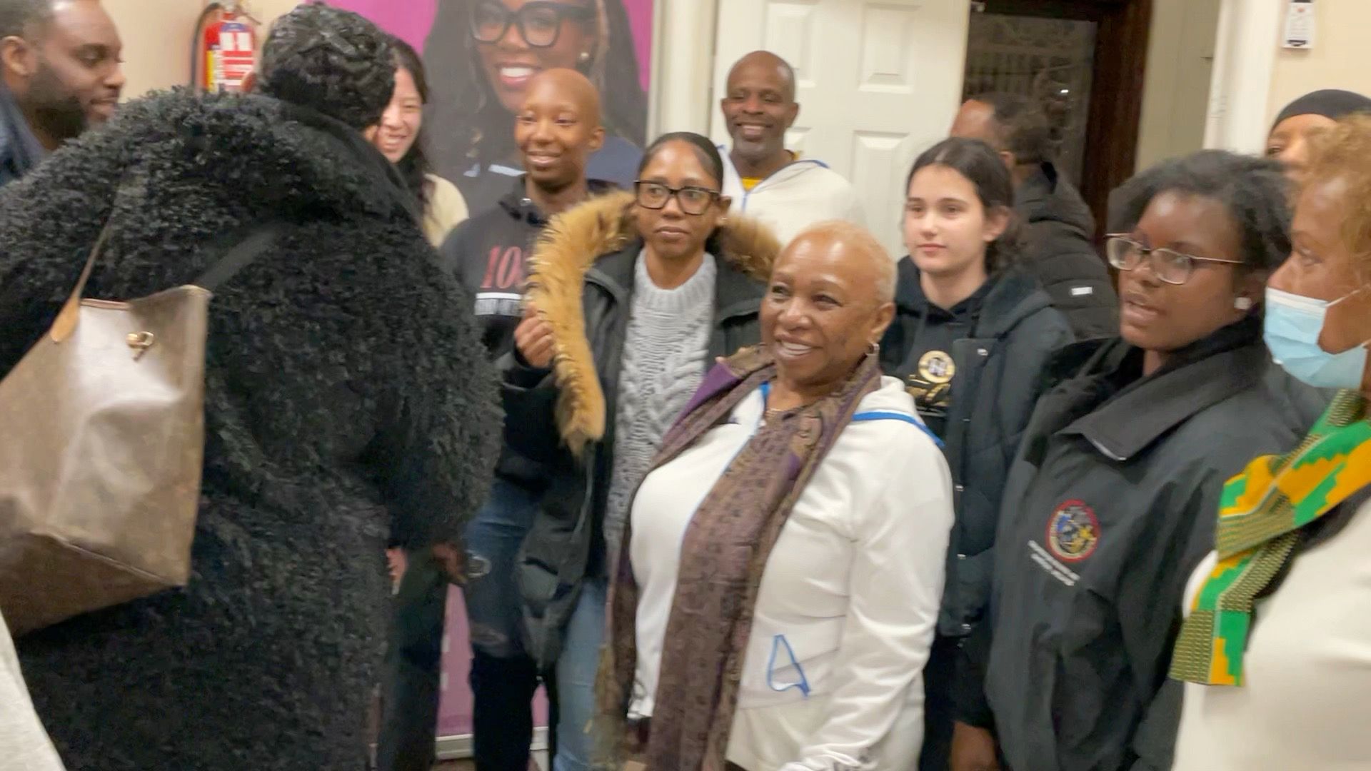 A group of people indoors, some bald, smiling. A banner is visible.
