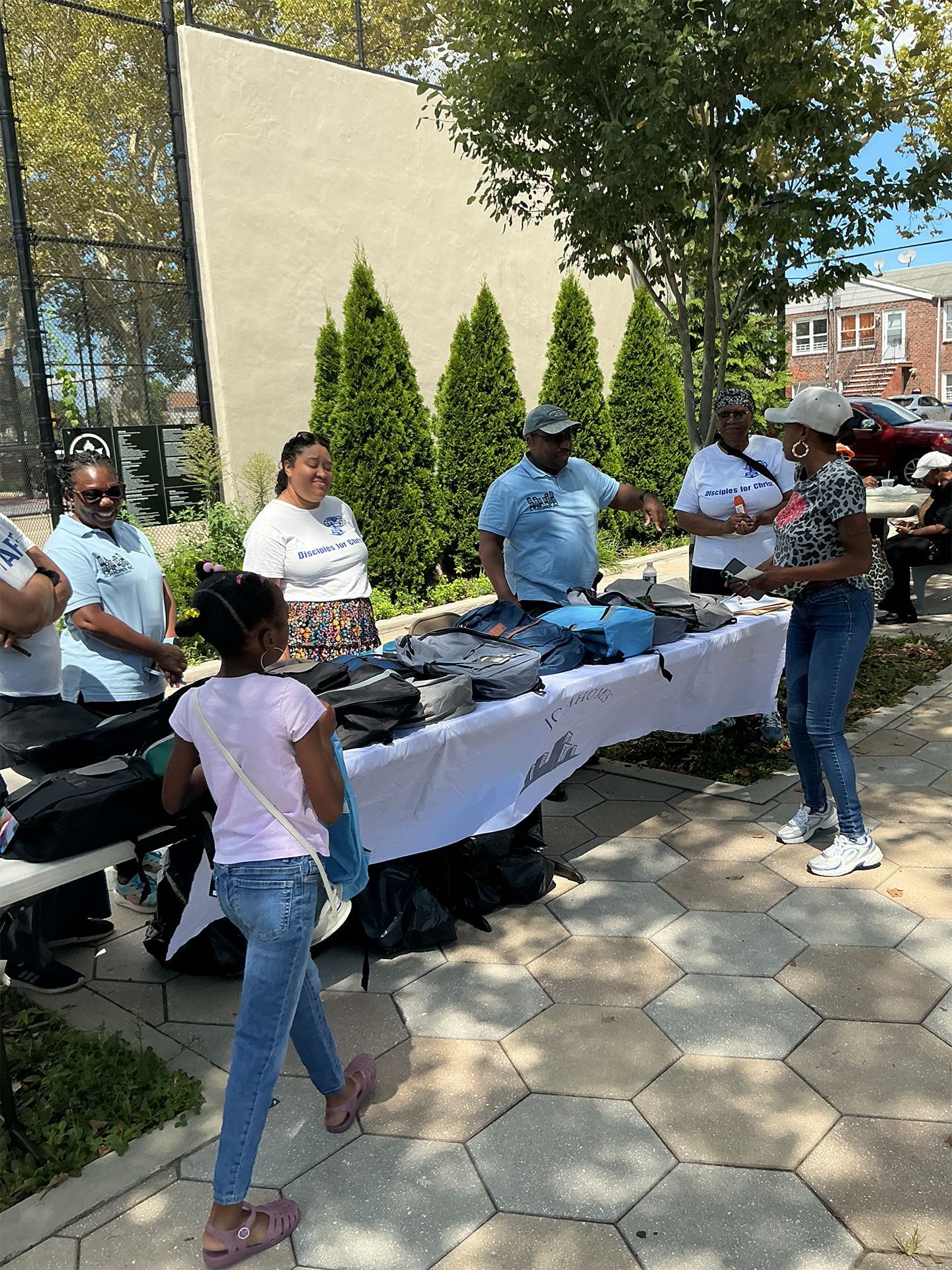 Community volunteers serving food at an outdoor table in a sunny park