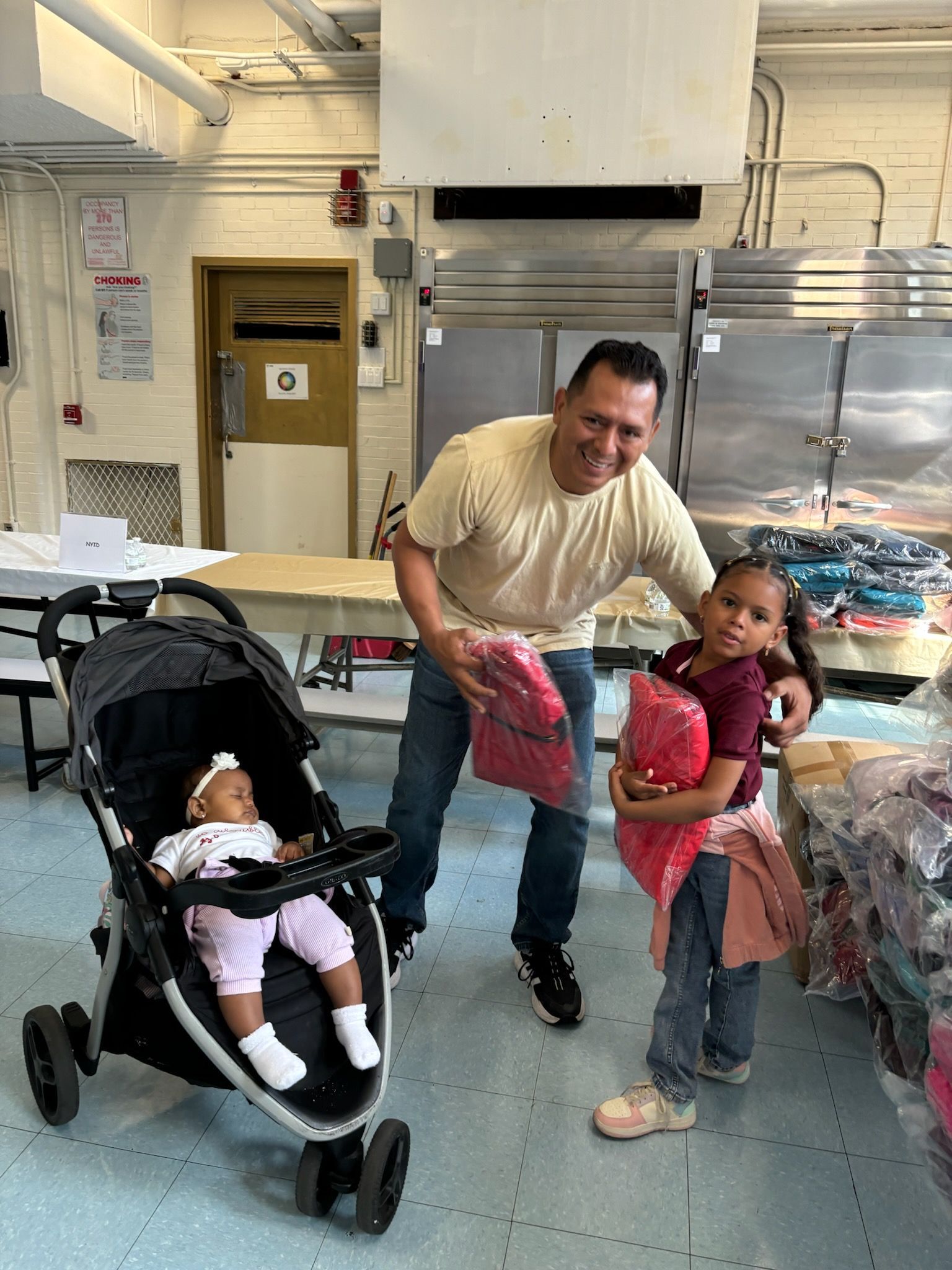 A man is standing next to two children and a baby in a stroller.