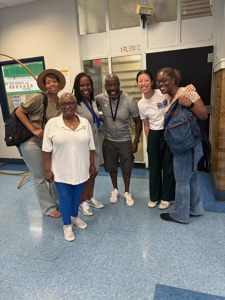 Group of smiling people in a hallway. Blue and white floor. Smiling faces.
