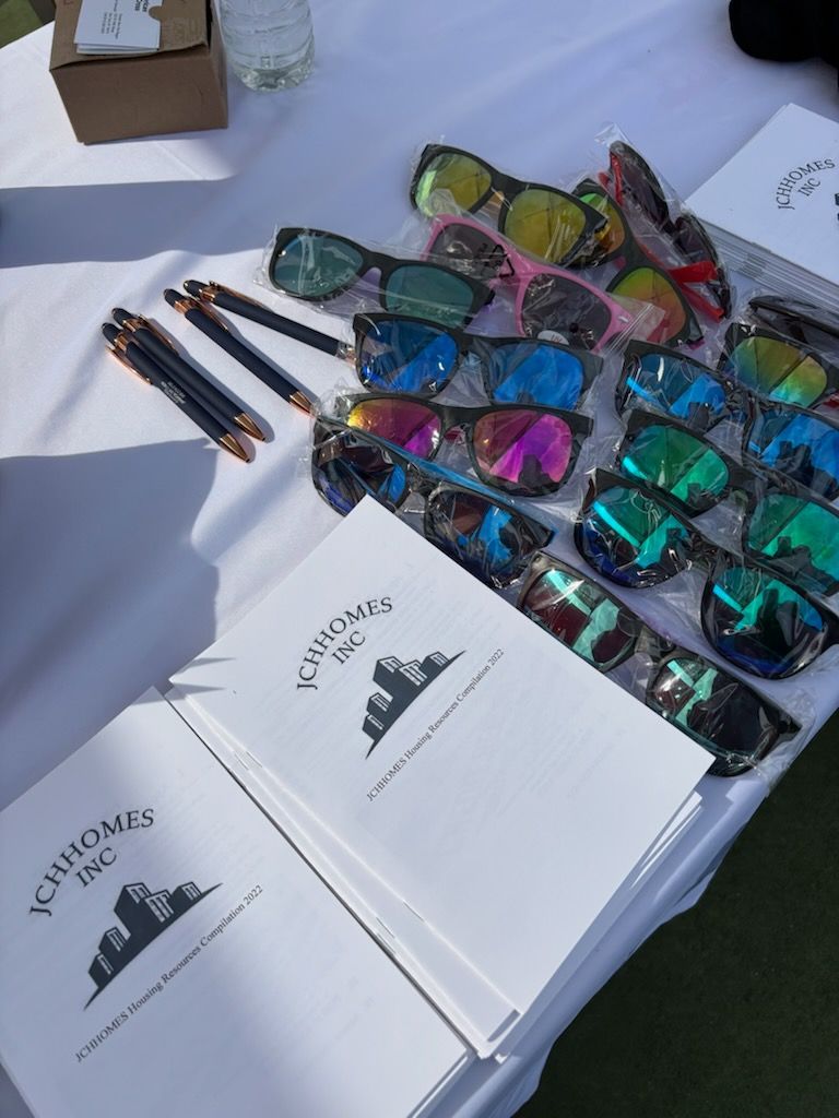 Table with sunglasses, pens, and branded notebooks laid out for display.