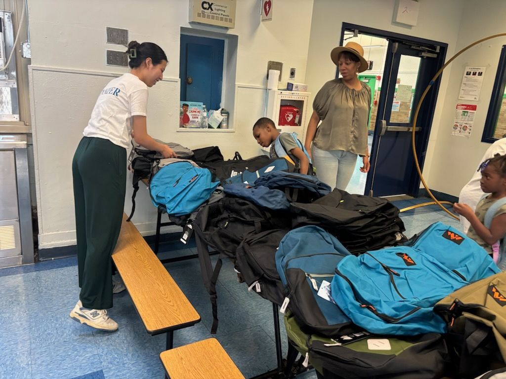 People gathering around backpacks, inside a building. One person packs, others look on.