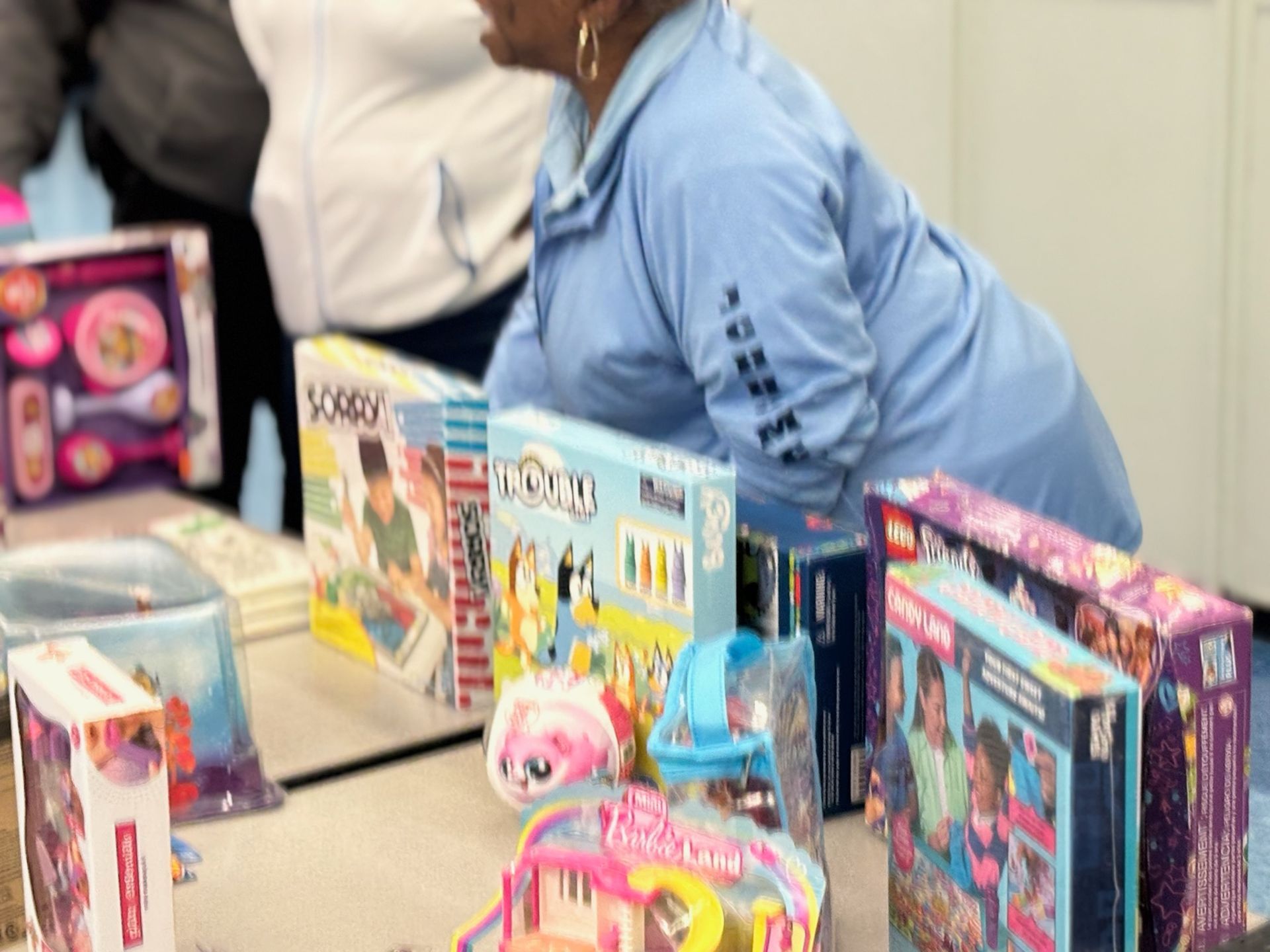 Person looking at a table displaying various children's toys, including board games and musical instruments.