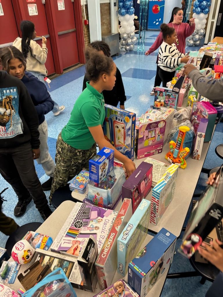 Children selecting gifts from a table at an event. Toys and books are on display.