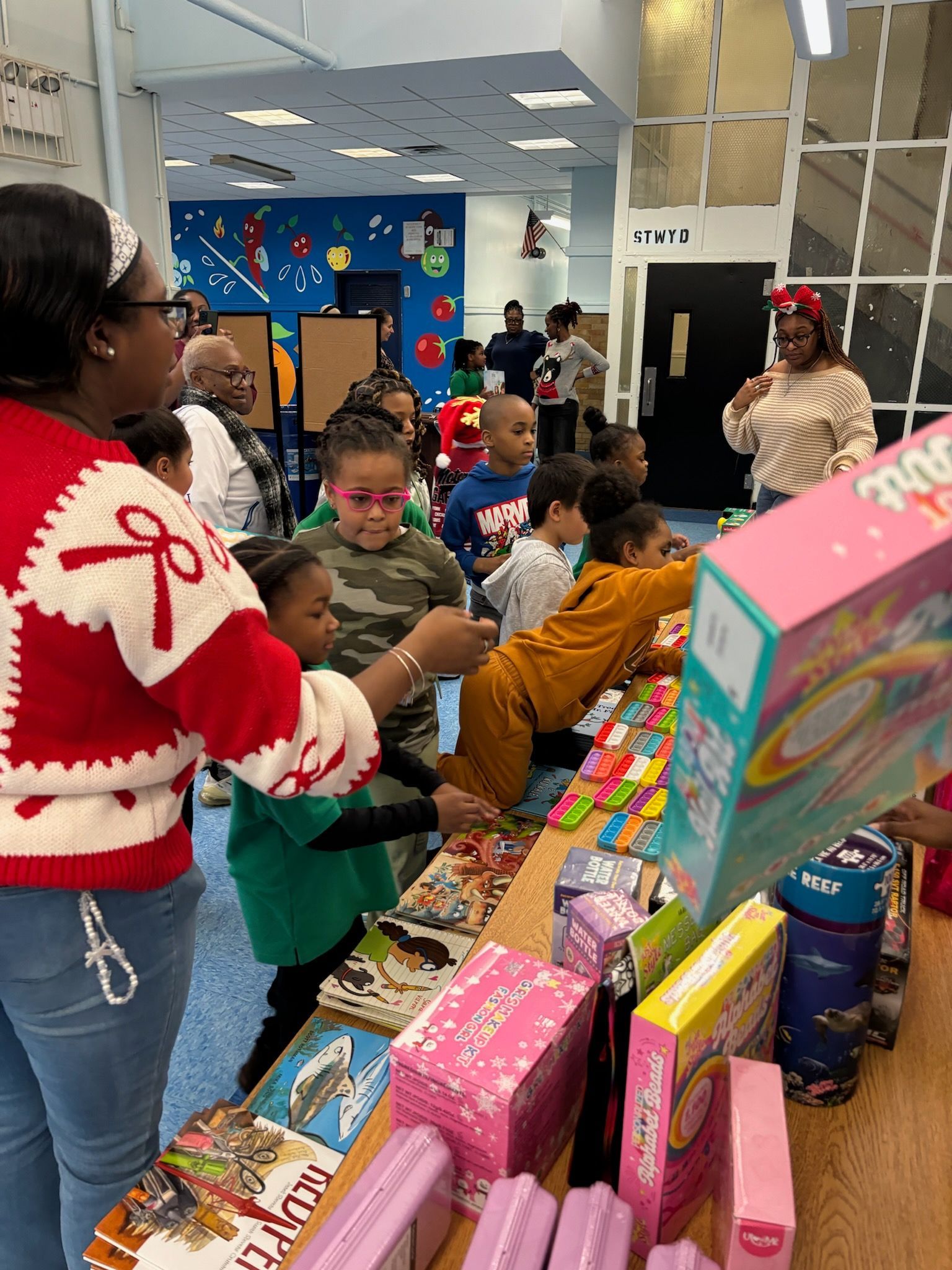 Children selecting toys at a table; adults assist.