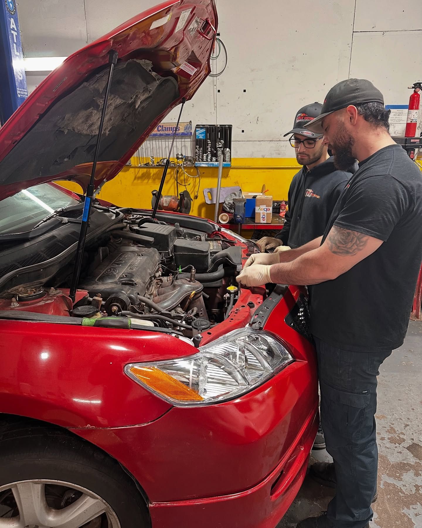 Technician Inspecting Red Car Engine In Service Bay | MLV Motoring