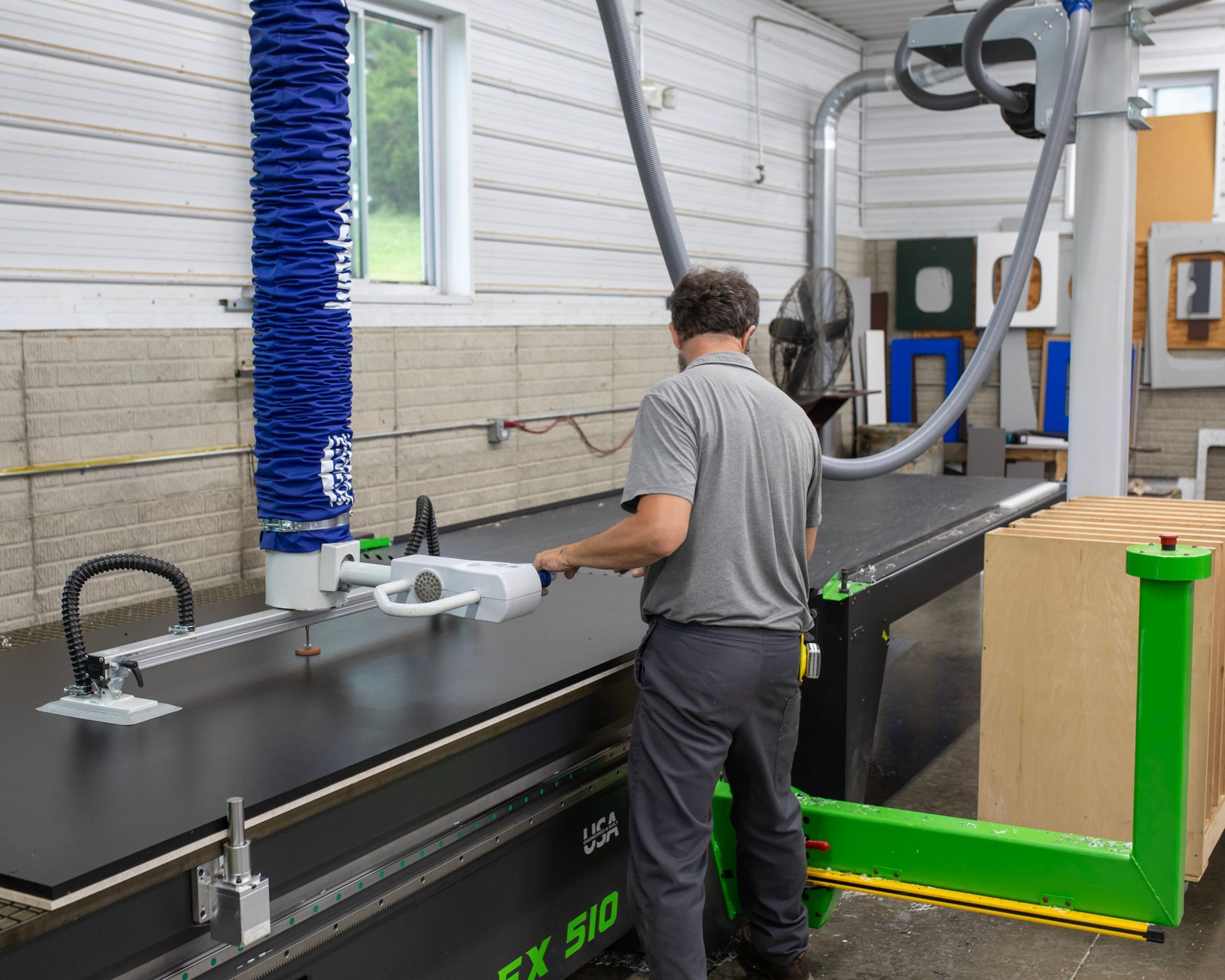 Worker operating a large black-and-green industrial machine in a workshop