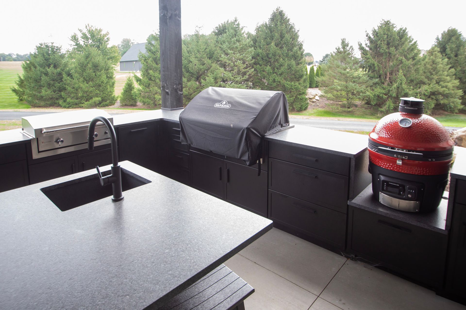 Covered patio with outdoor grill, dining table, and green backyard view