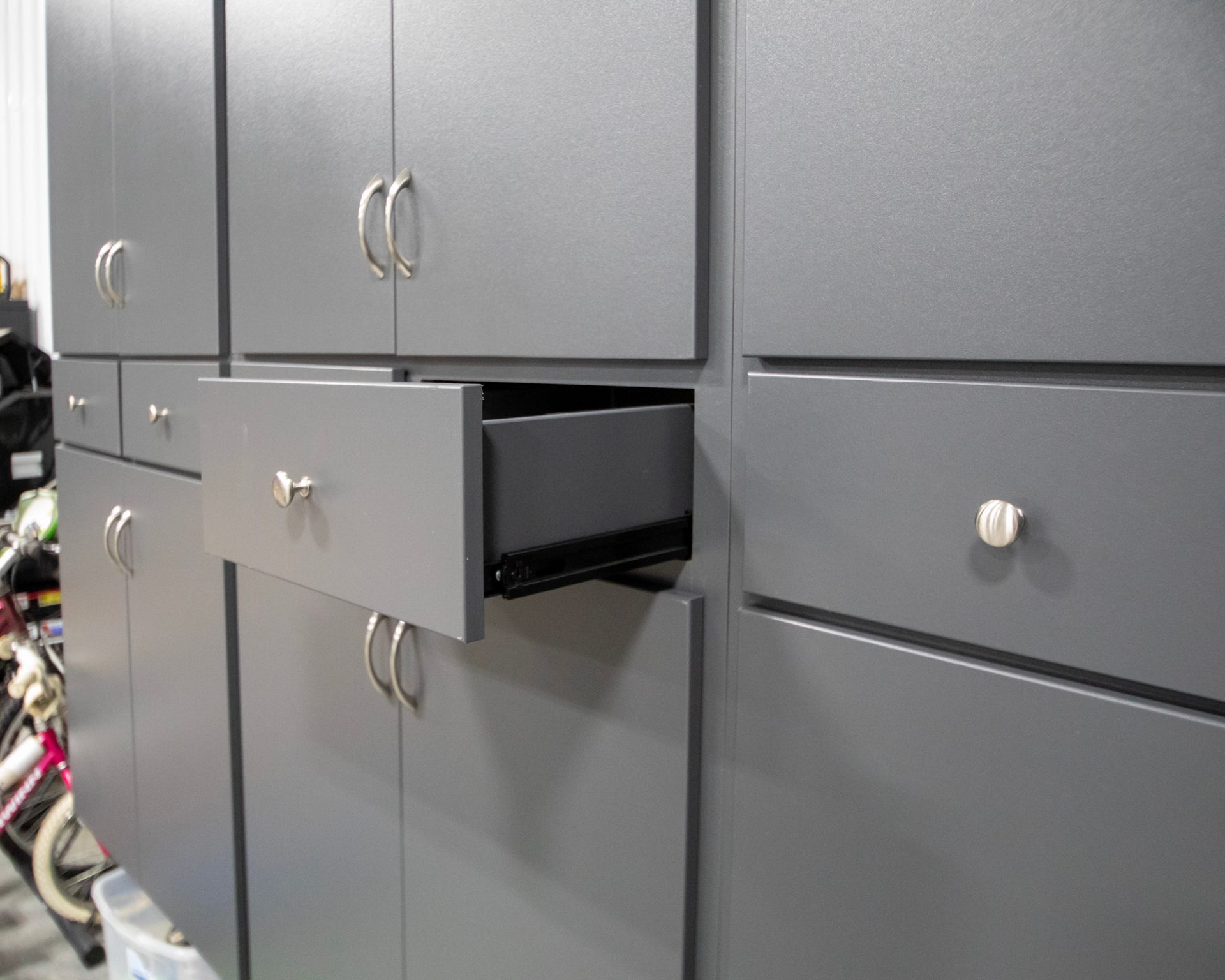 Gray storage cabinets with one drawer pulled open, revealing a black interior.