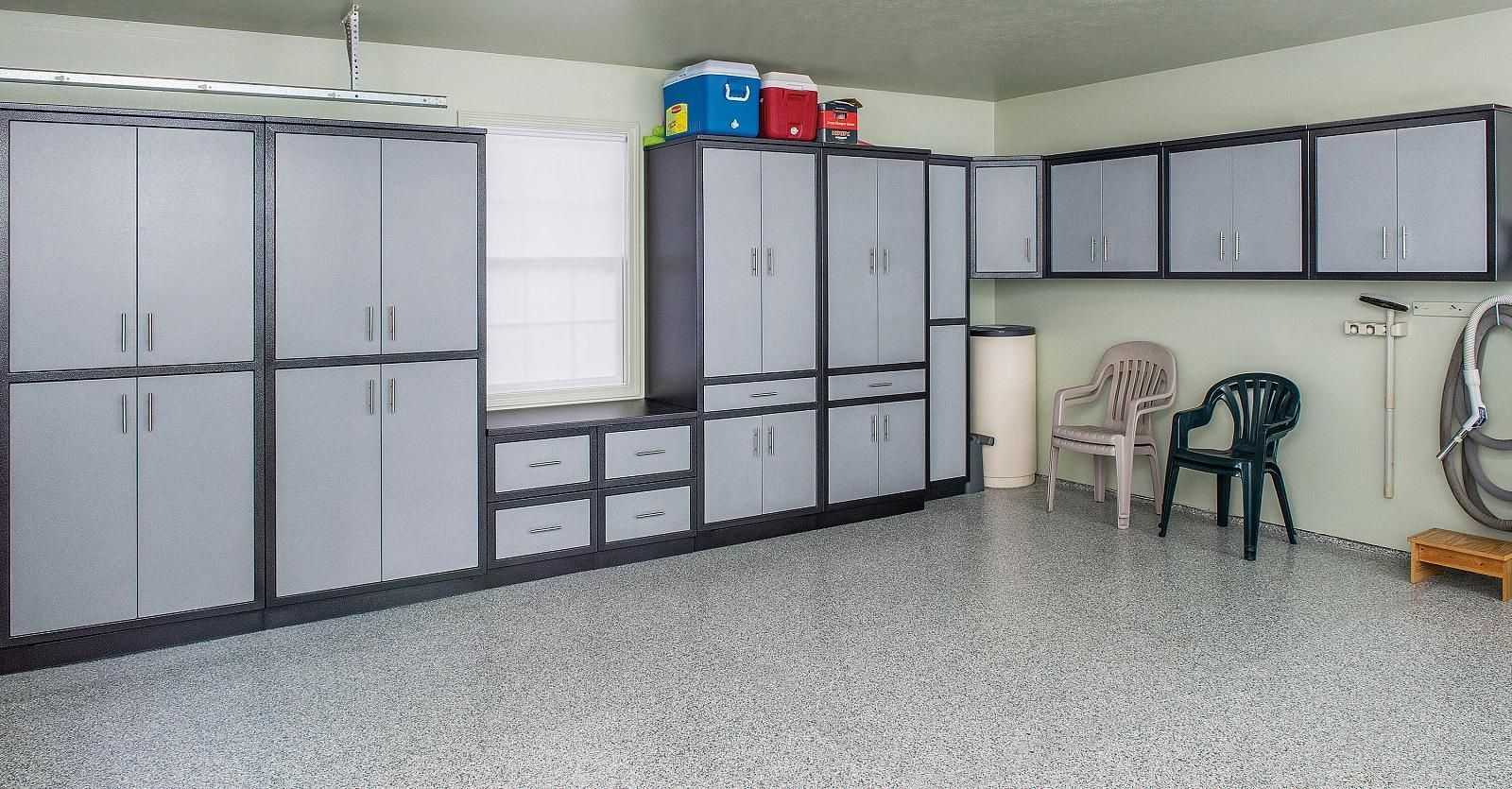 Garage with gray storage cabinets, stacked bins, folding chairs, and a speckled floor.