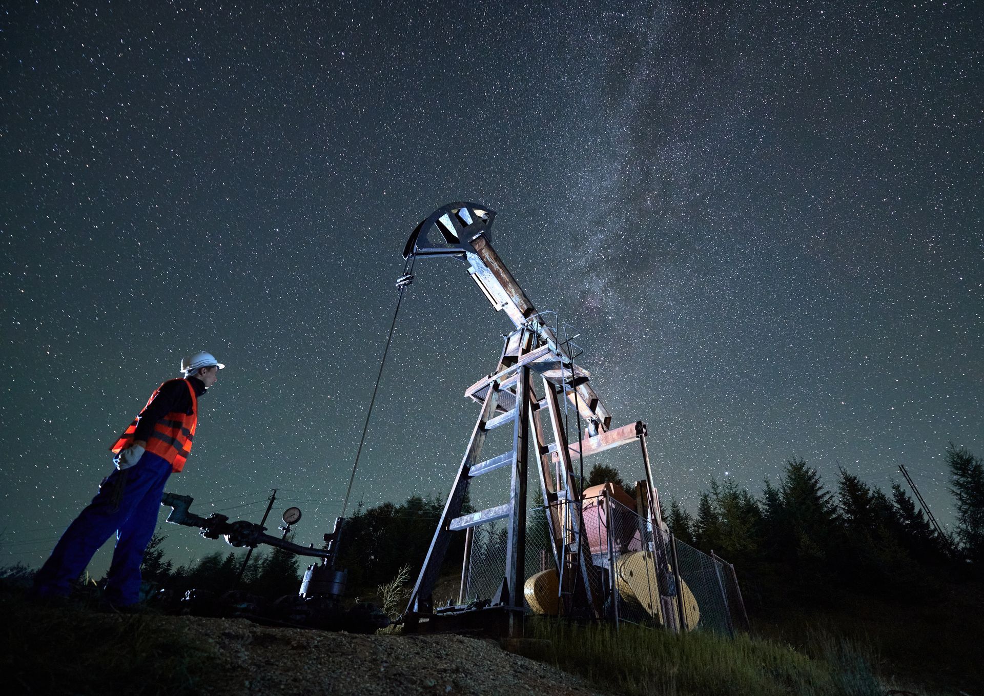Person standing by a telescope under a starry night sky