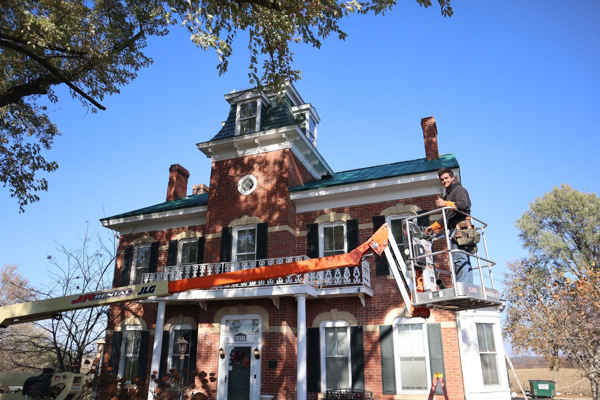 Joe Harrington poses on lift in front of house.