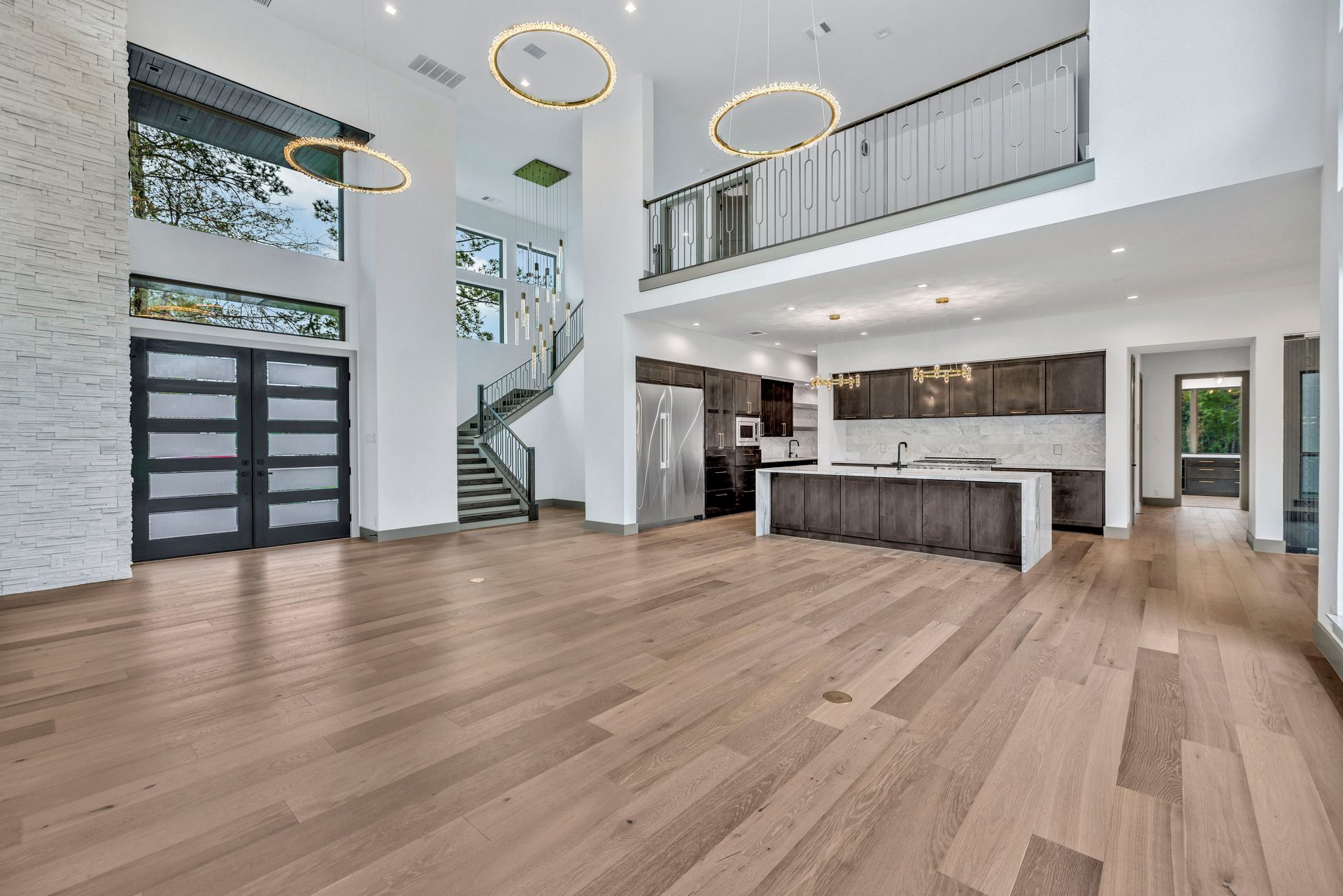 A large empty room with hardwood floors and a kitchen.