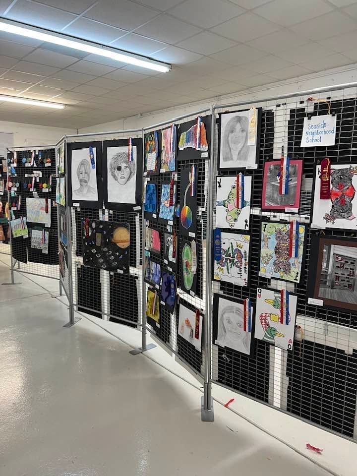 Art display on hallway walls with colorful student drawings and posters in a school corridor