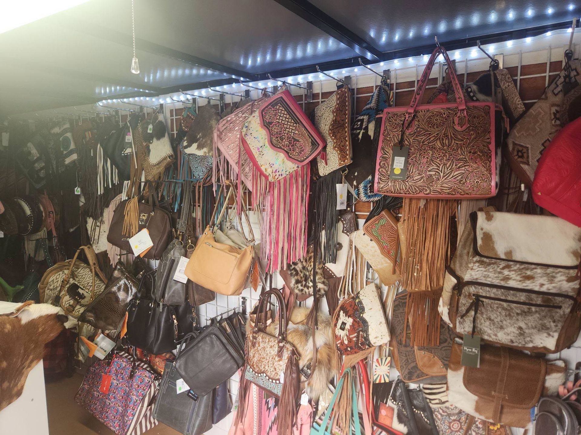Display of hanging handbags and purses in a dimly lit market stall
