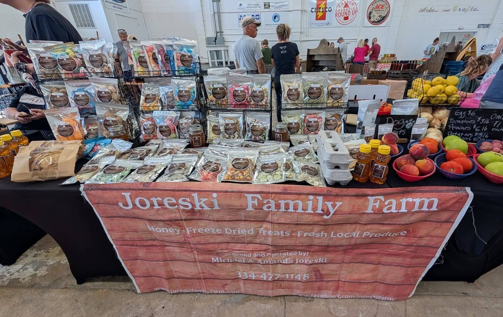 Vendor table with handmade crafts, cards, and trinkets displayed at an indoor fair booth