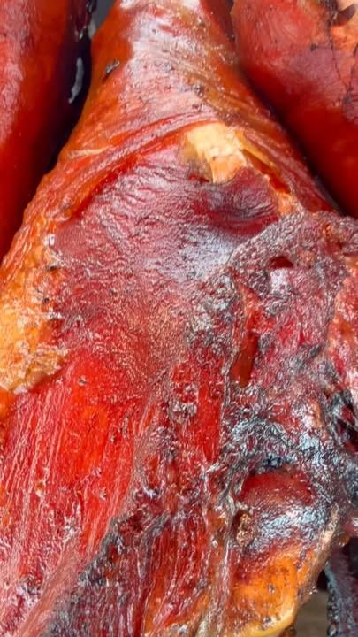 Close-up of a glossy red-brown roasted meat surface with charred and golden edges