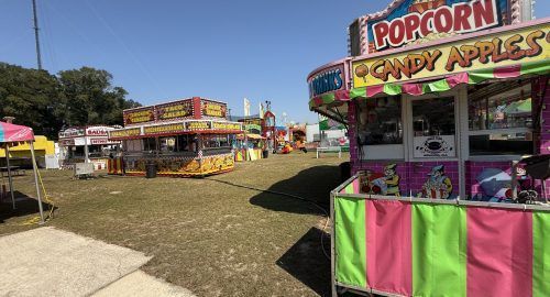 Fairground food stalls with popcorn and candy apples under a bright blue sky