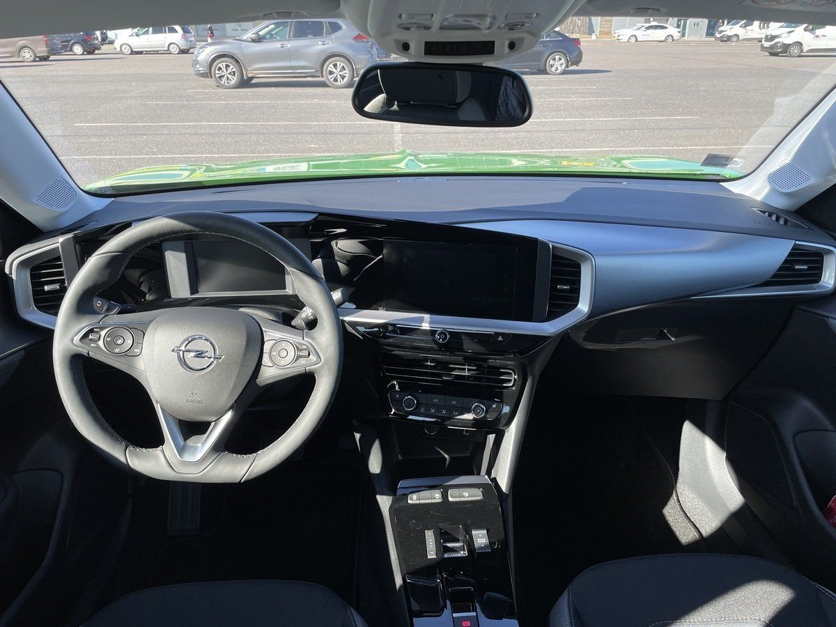 Zaļas automašīnas salons ar stūri un instrumentu paneli.
