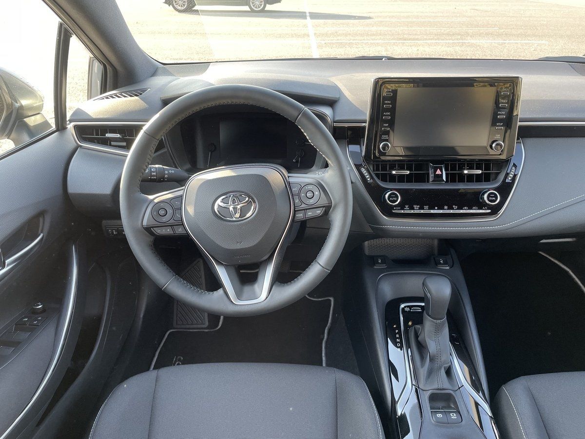 Toyota Corolla salons ar stūri un radioaparātu.
