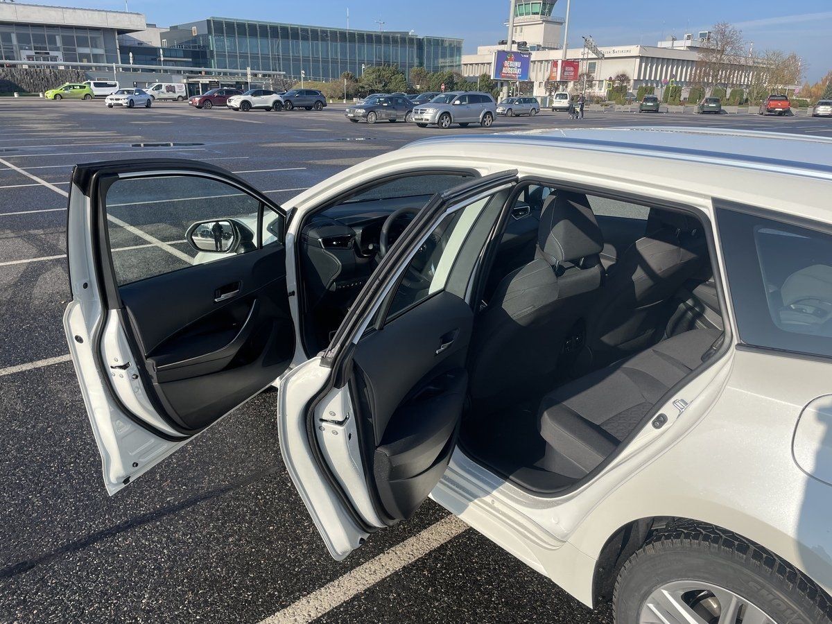 Balta automašīna ar atvērtām durvīm stāvvietā