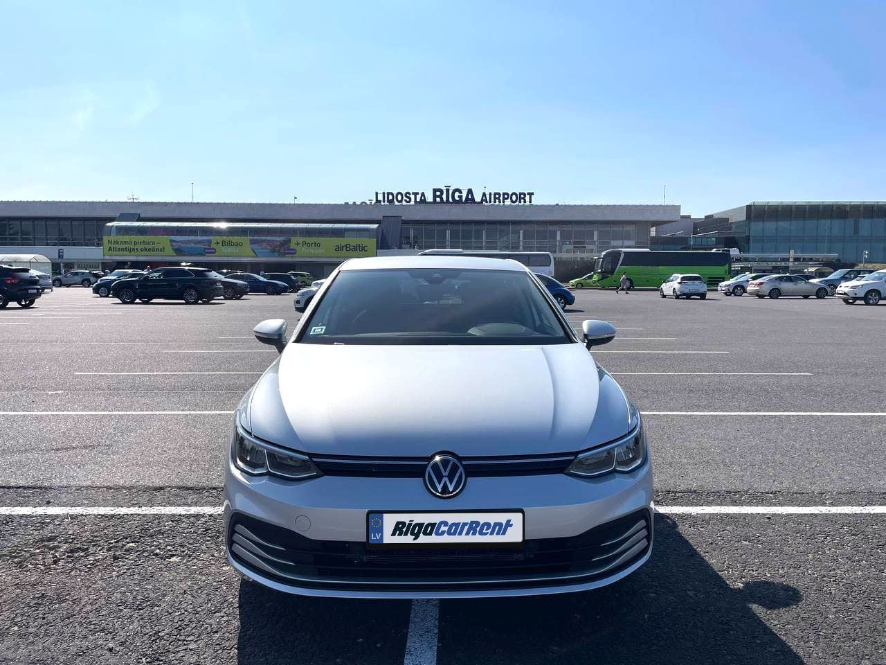 Balts Volkswagen Golf ir novietots autostāvvietā.