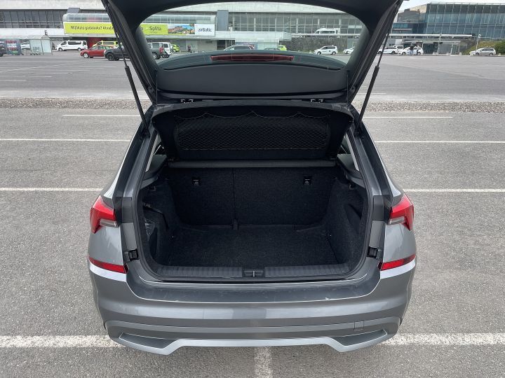 Autostāvvietā ir atvērts automašīnas bagāžnieks.
