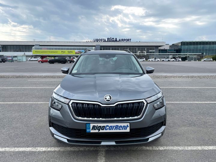 Škoda automašīna ir novietota stāvvietā lidostas priekšā.