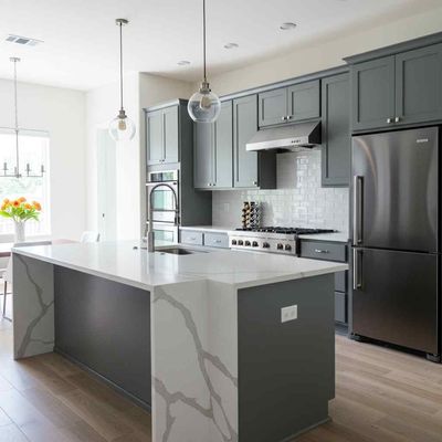 Modern kitchen with gray cabinets, marble island, stainless appliances, and pendant lights
