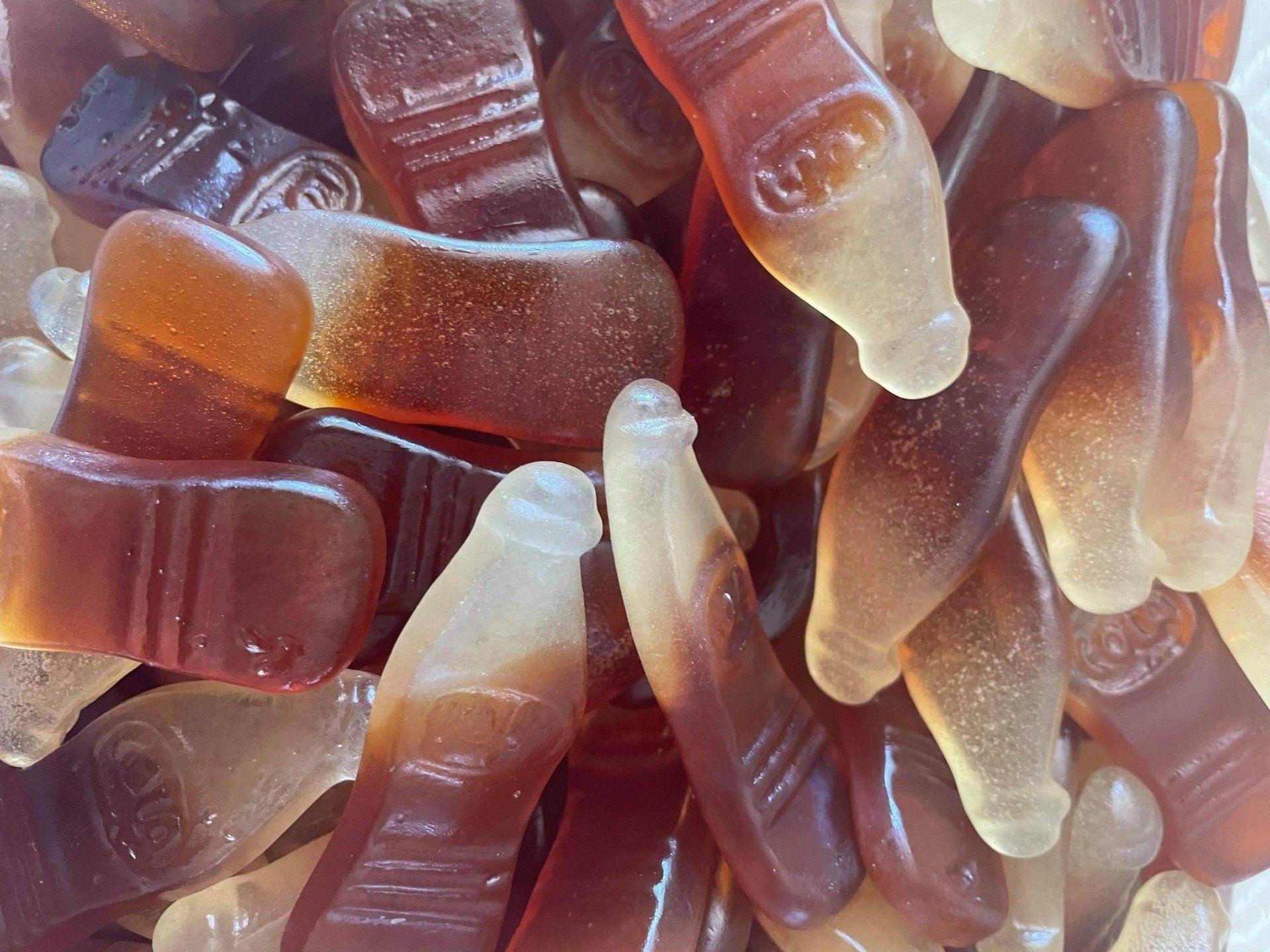 A close up of a pile of gummy cola bottles