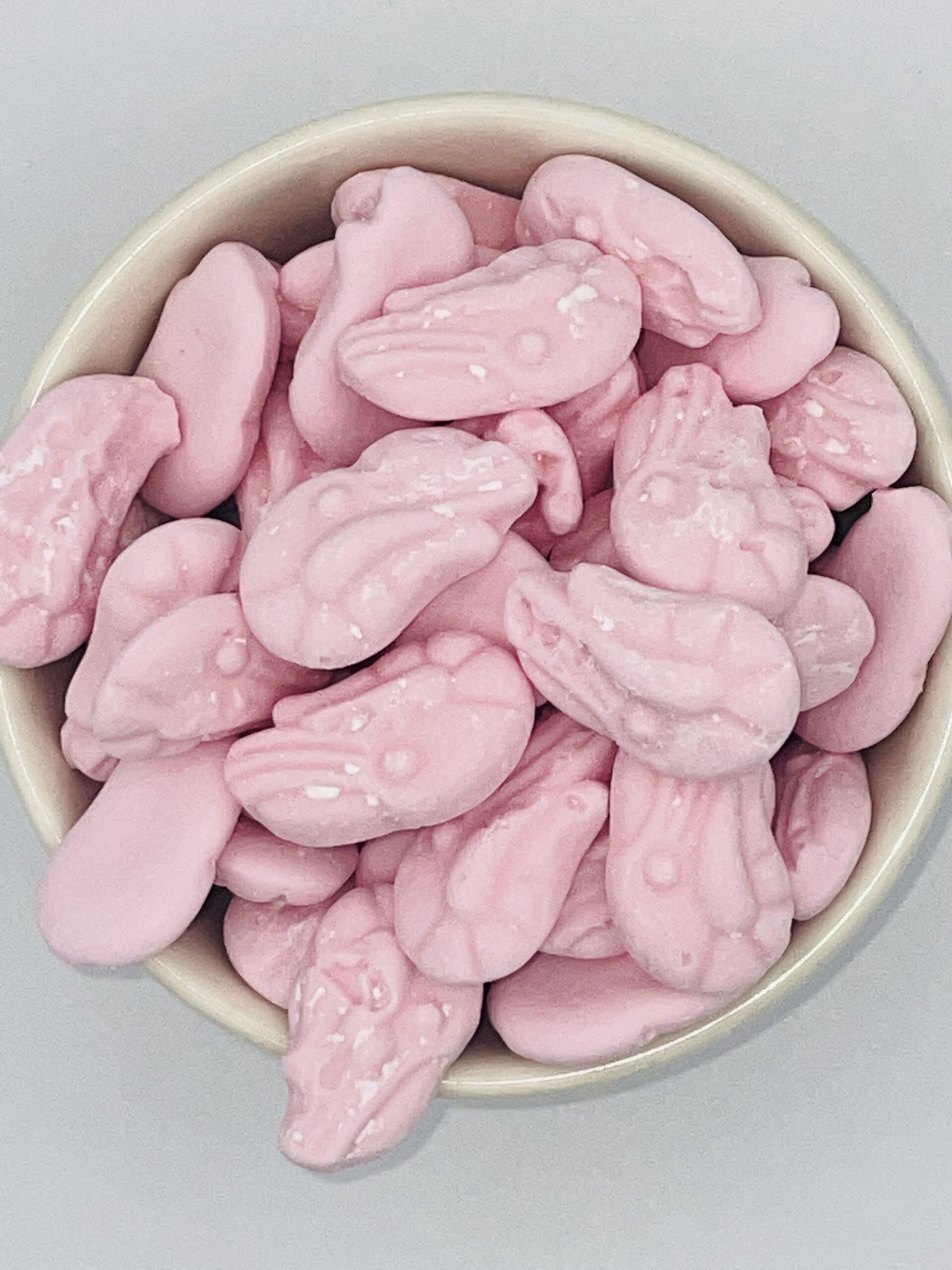 A bowl filled with pink candy in the shape of cars