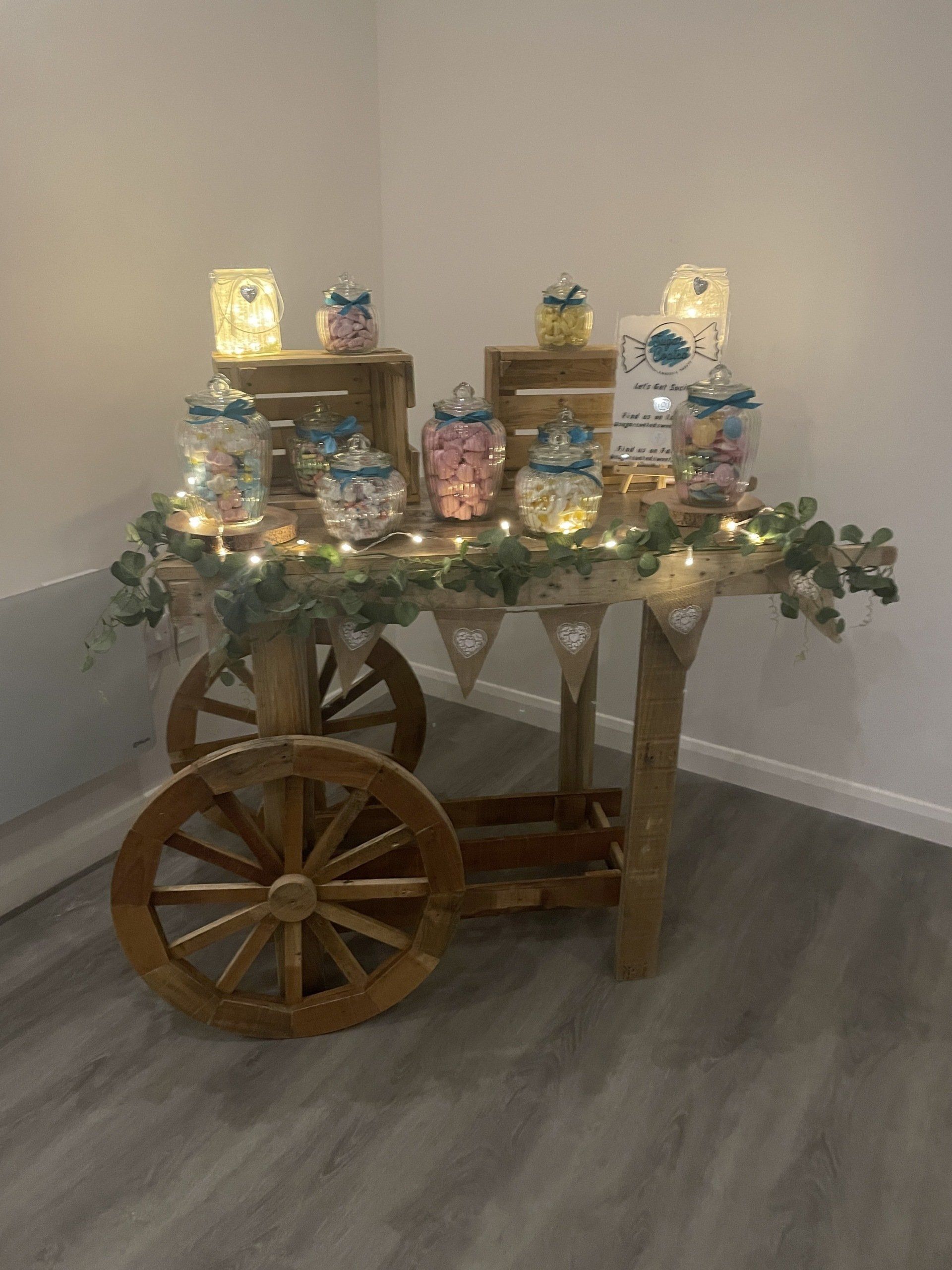 a wooden cart filled with jars of candy is sitting in a room .