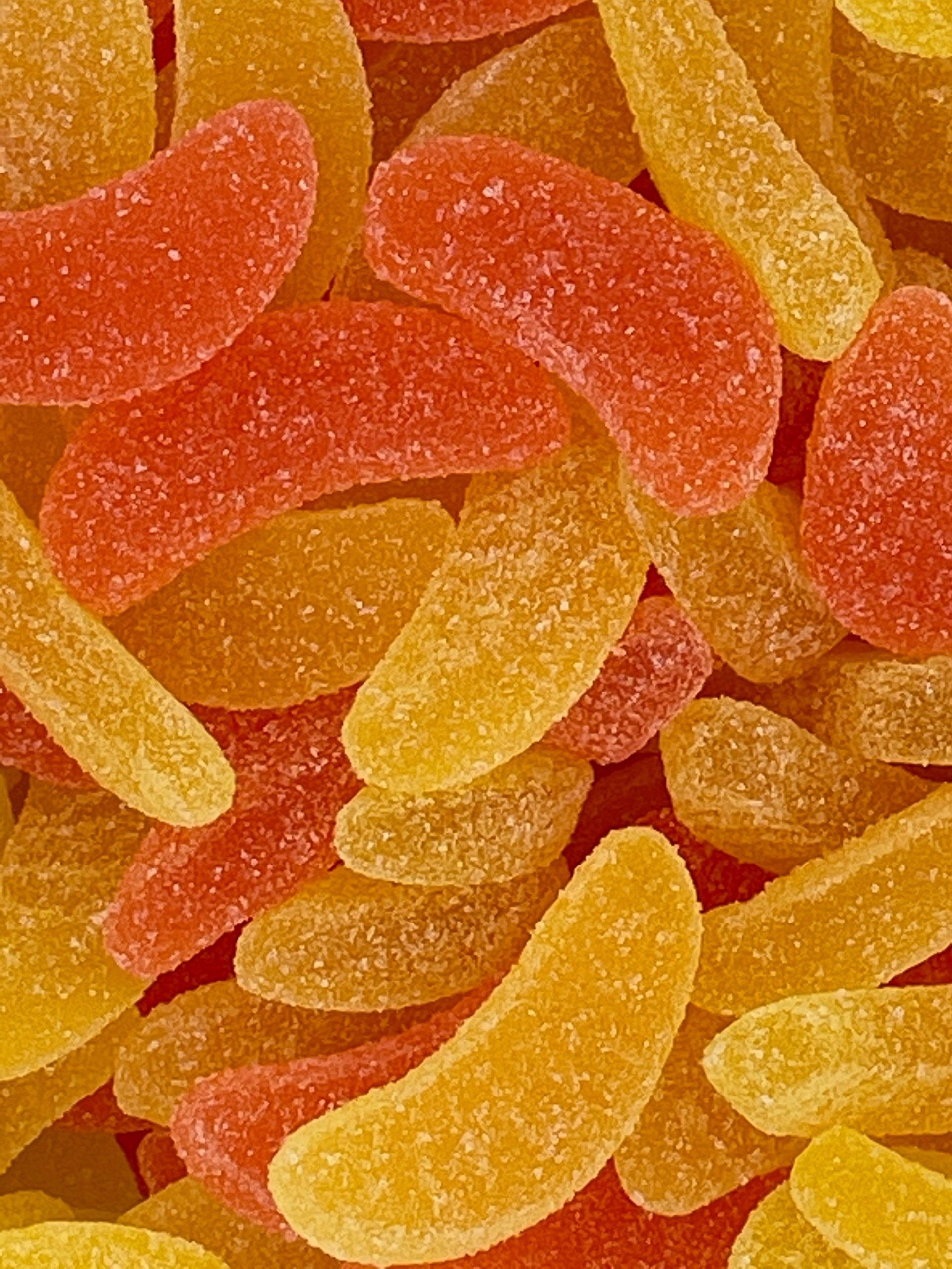 A close up of a pile of colorful gummy bananas.
