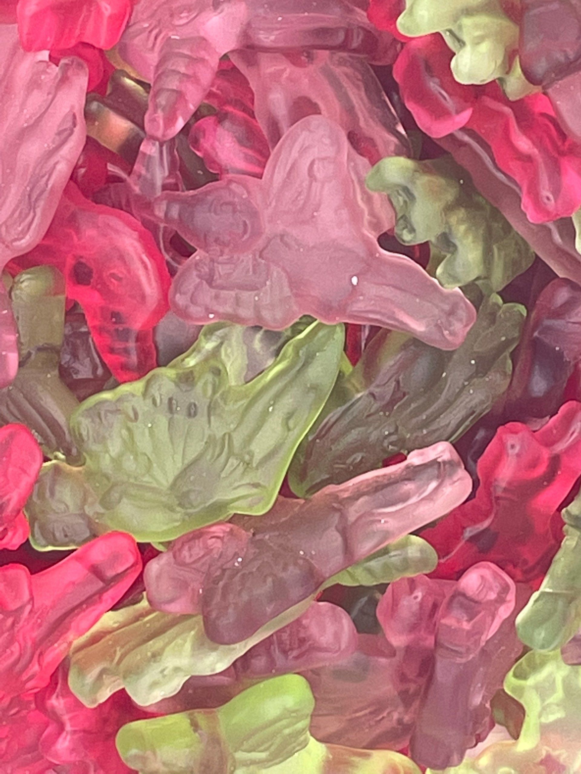 A close up of a pile of gummy frogs in different colors.