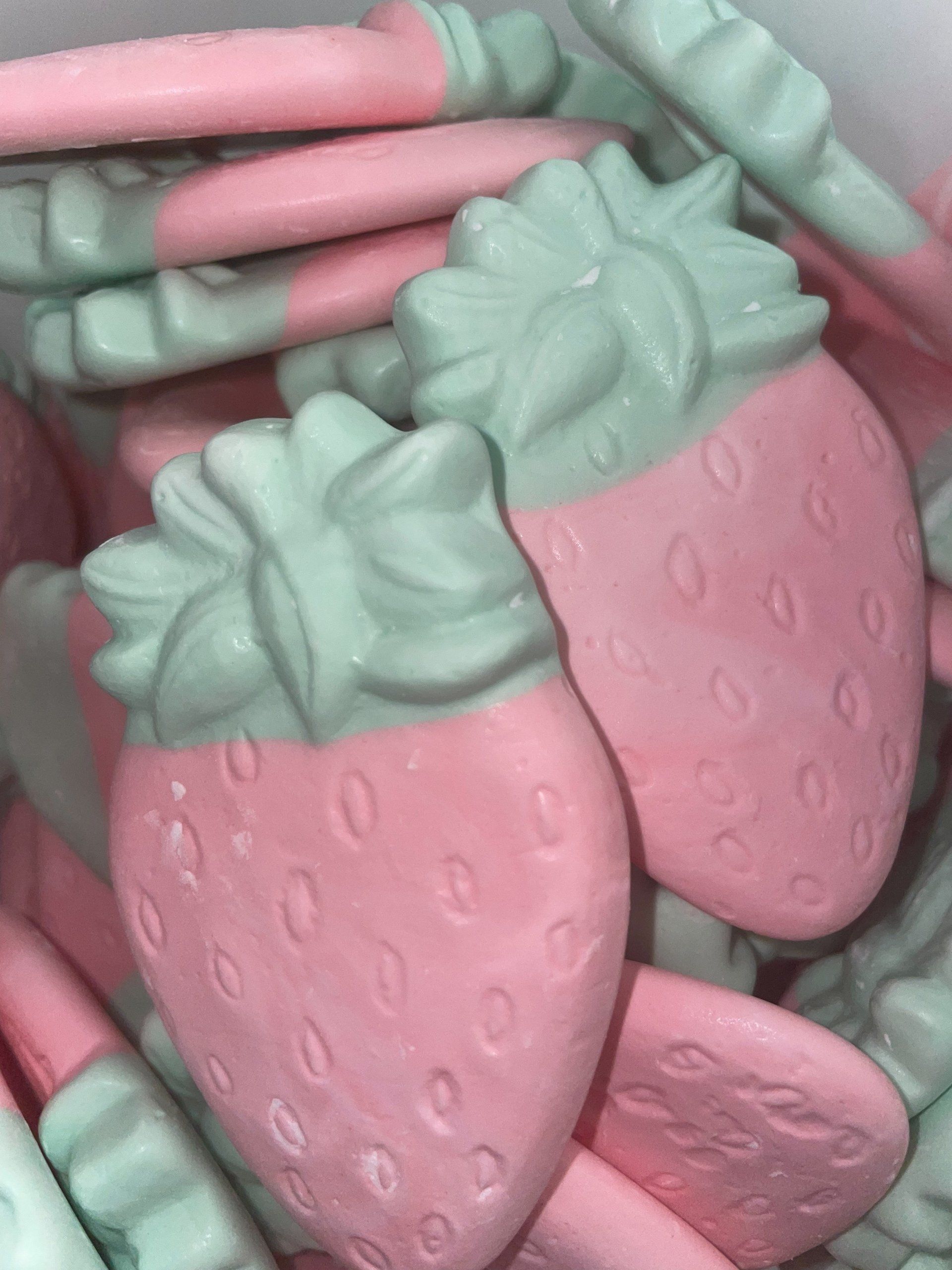 A pile of pink and green strawberry shaped candy.