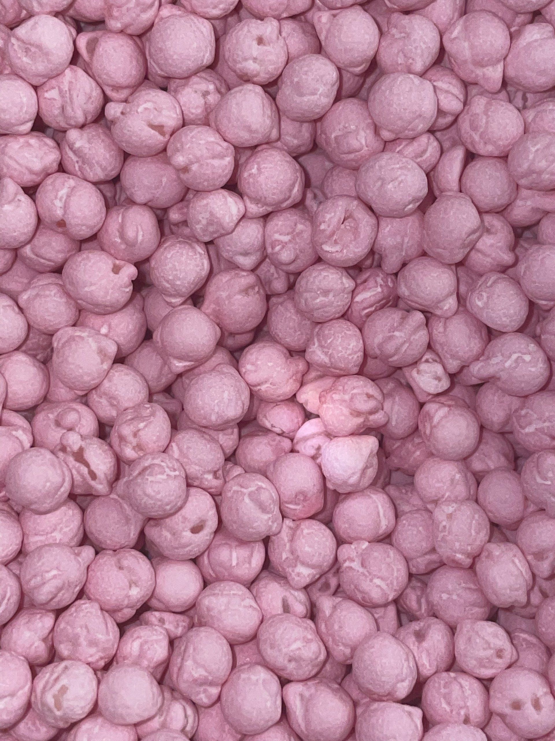 A close up of a pile of pink peanuts.