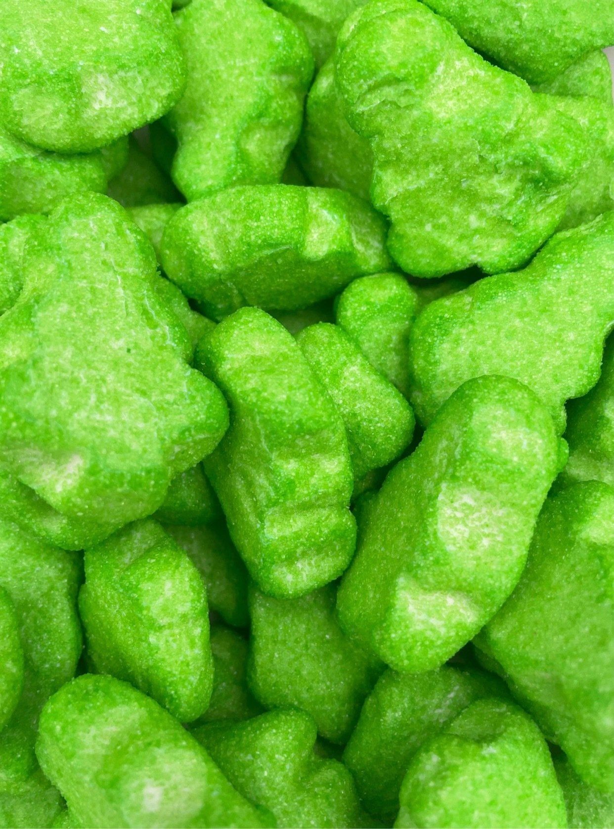 A close up of a pile of green gummy bears.