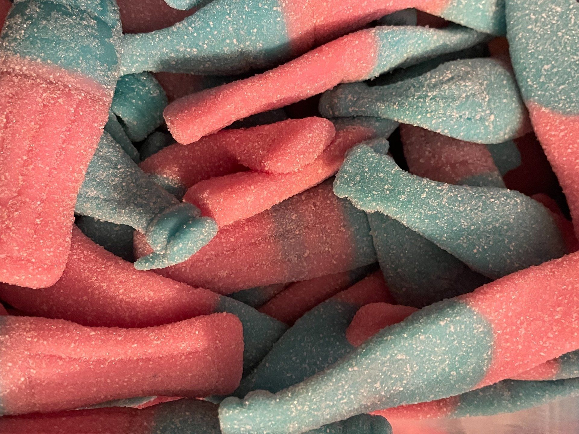 A close up of a pile of pink and blue gummy bottles.