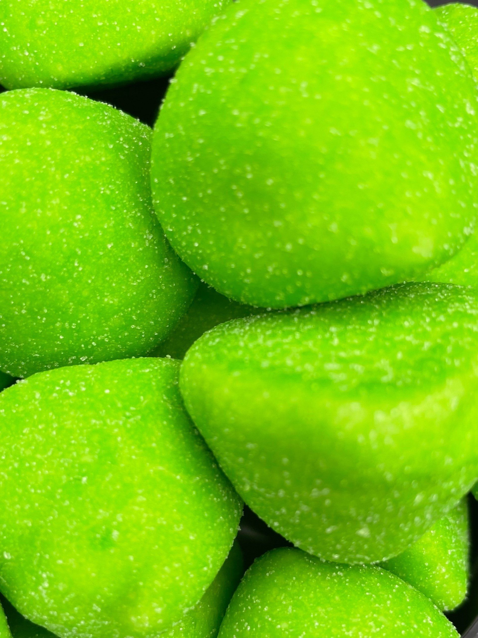 A close up of a pile of green gummy candies.
