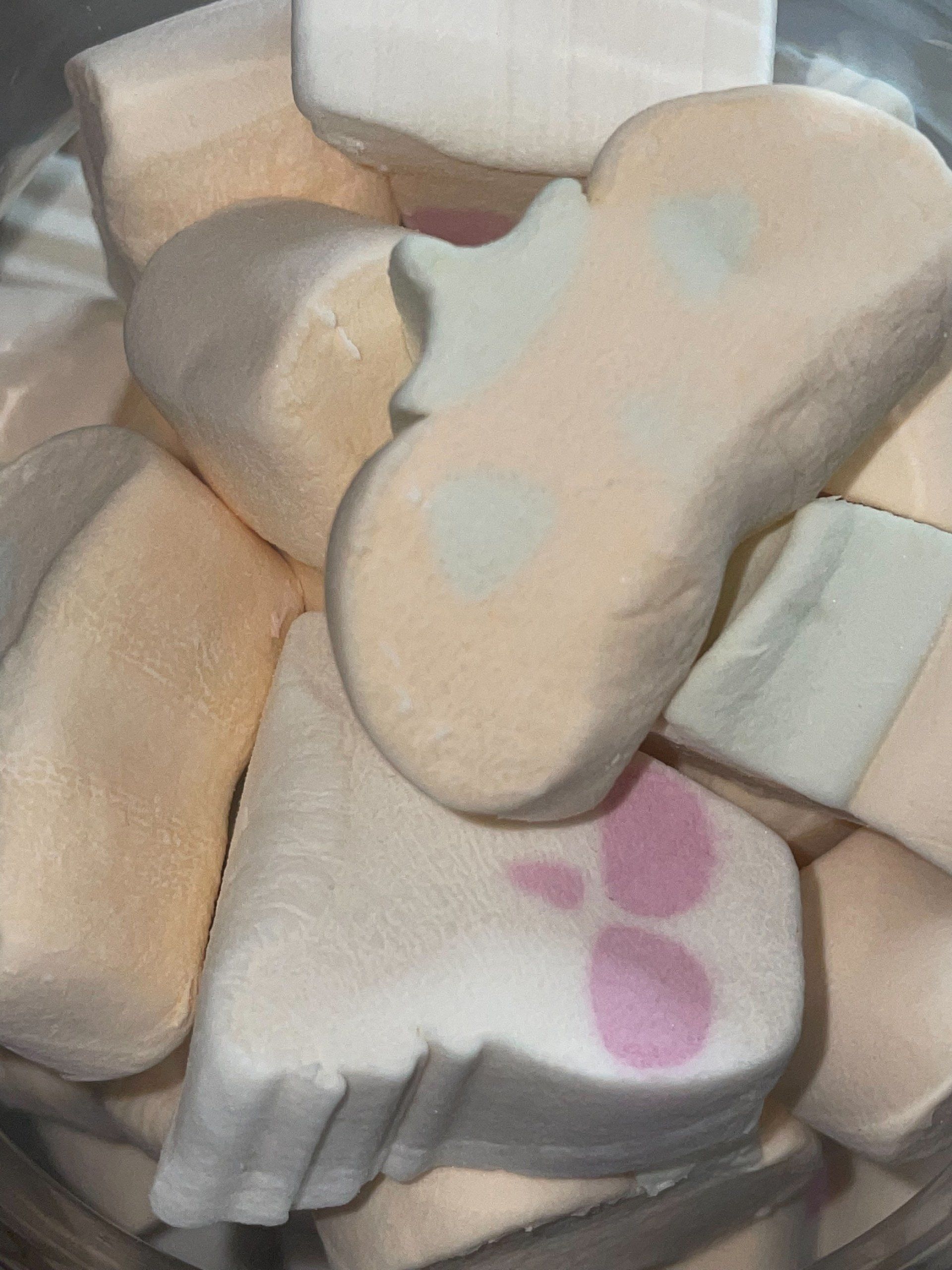 A close up of a bowl of marshmallows in the shape of a cat 's paw.