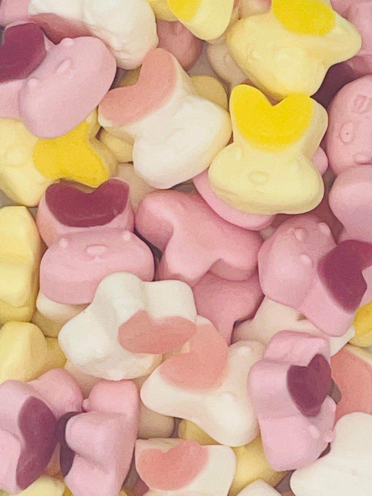 A pile of pink and yellow marshmallows with hearts on them
