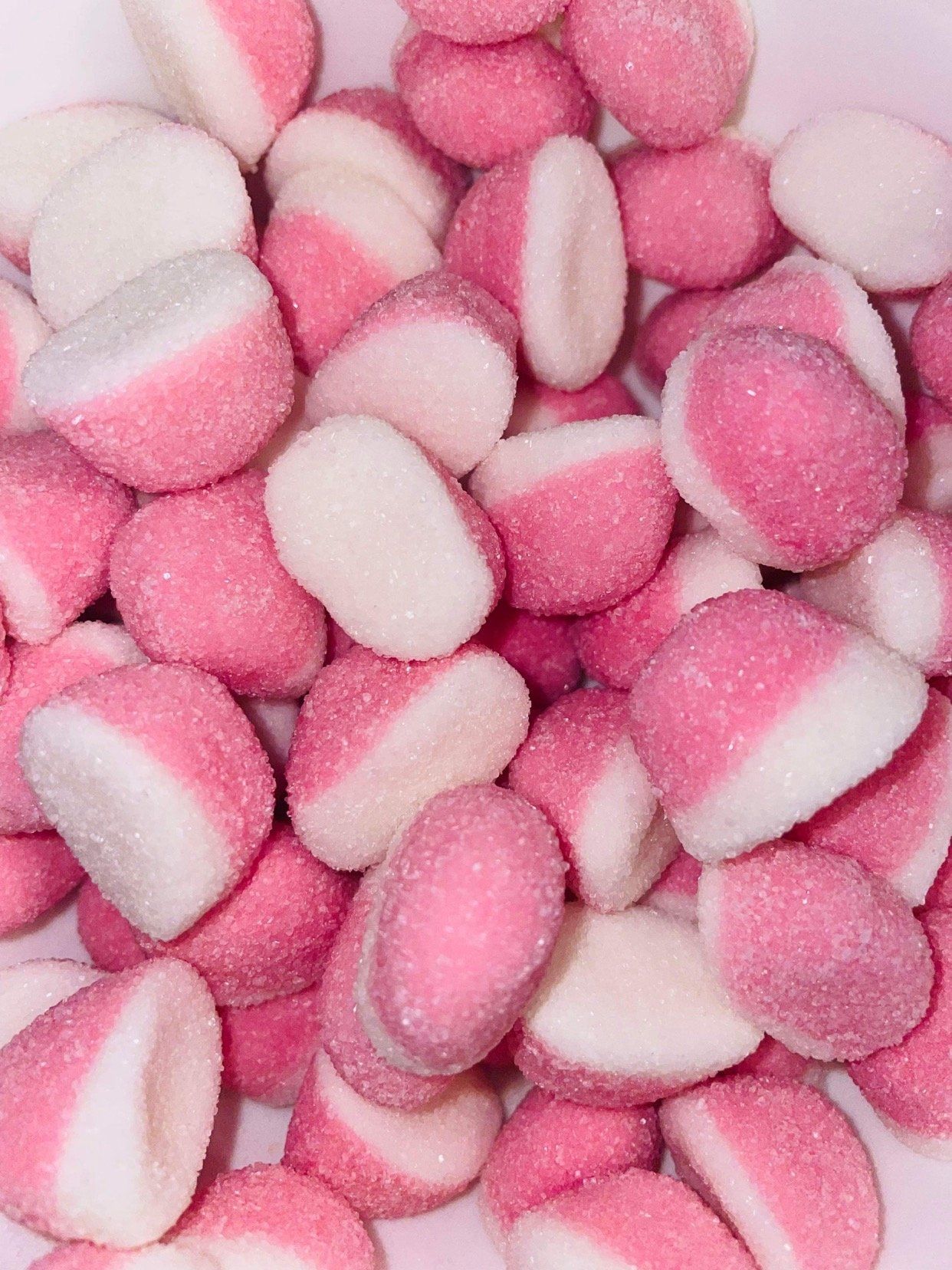 A pile of pink and white candy on a white surface