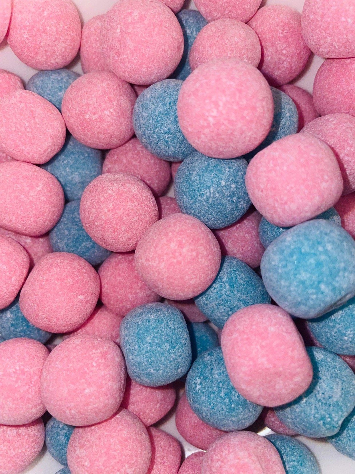 A pile of pink and blue candy balls on a white surface.