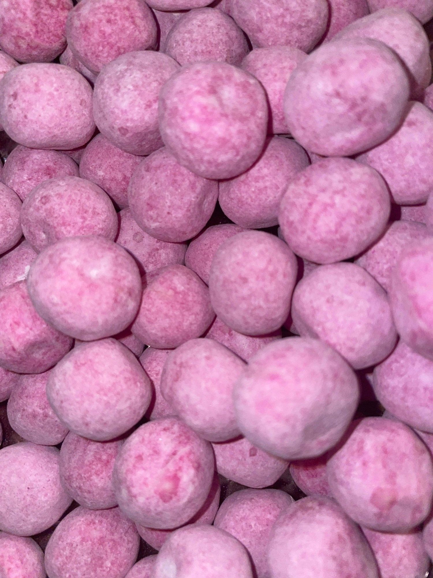 A close up of a pile of pink candy balls.