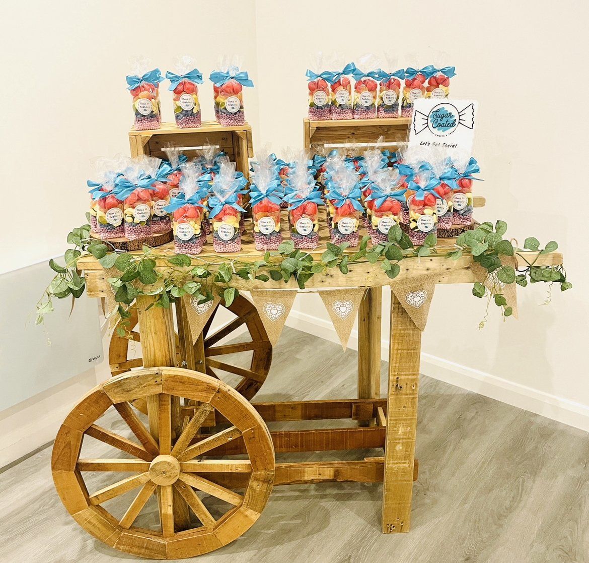 A wooden cart filled with candy is sitting on a wooden floor.