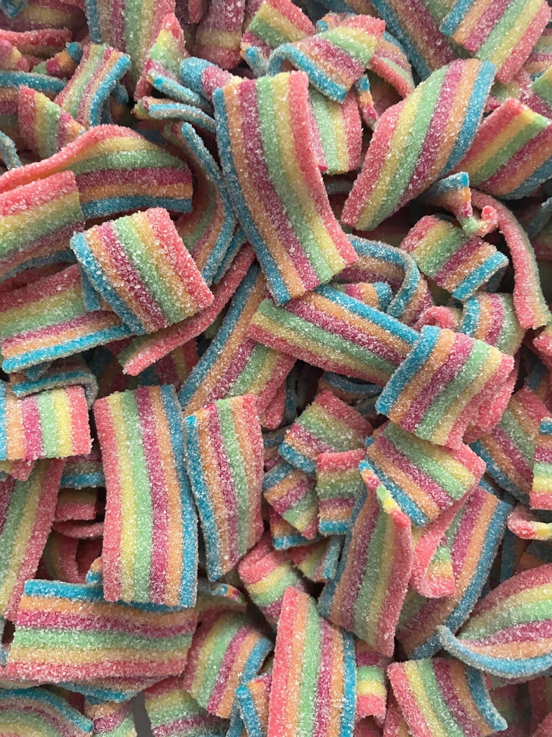 A pile of rainbow colored gummy candies on a table.
