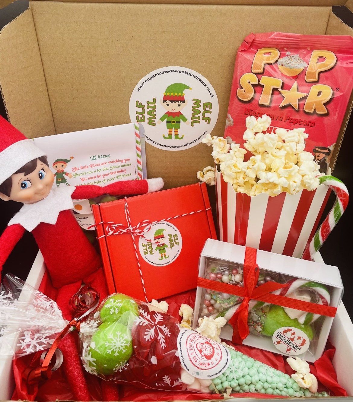 An elf on the shelf is in a box filled with candy and popcorn