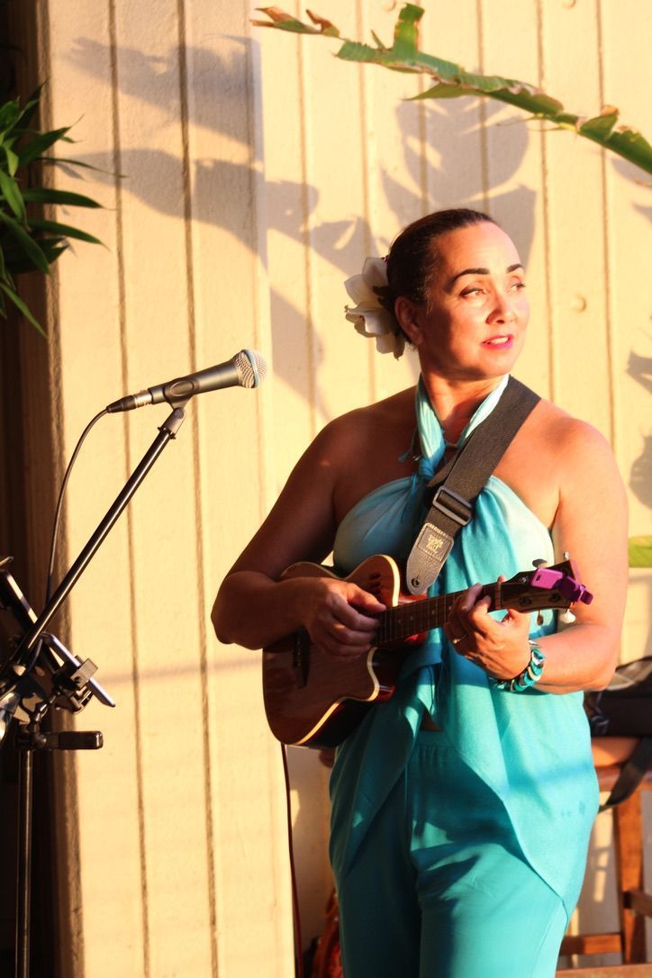 a woman in a blue dress is playing a guitar in front of a microphone